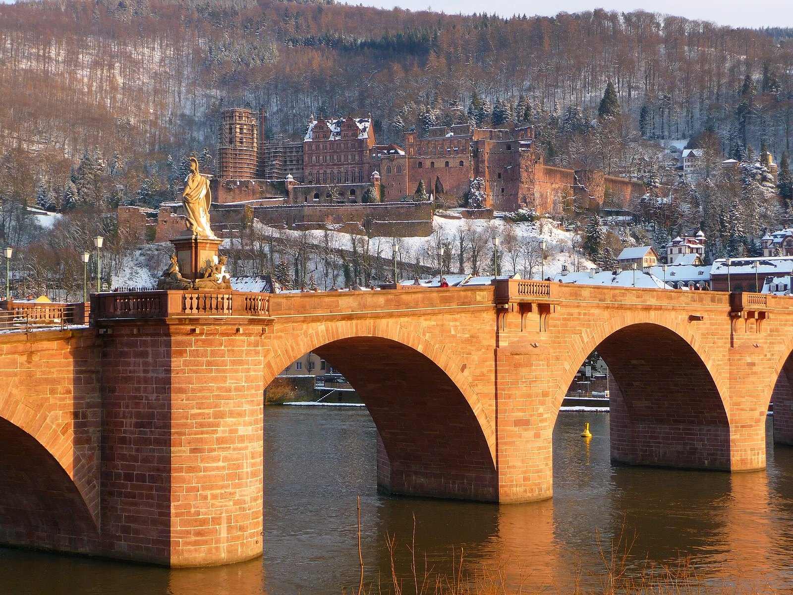 Alte Brücke im Abendlicht, dahinter das verschneite Schloss